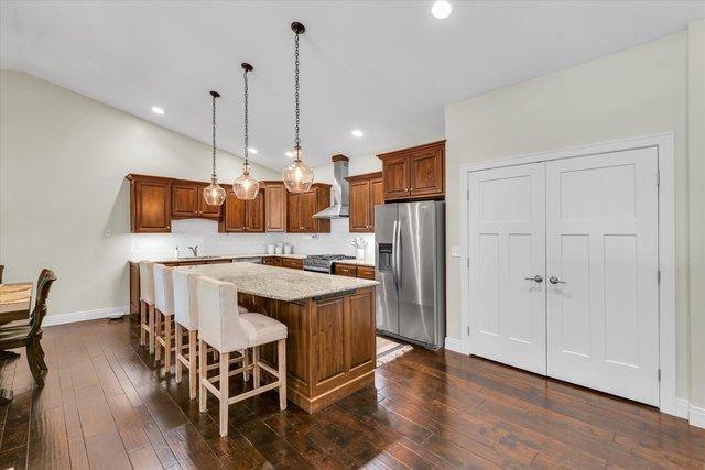 kitchen featuring appliances with stainless steel finishes, ventilation hood, vaulted ceiling, decorative light fixtures, and a kitchen island