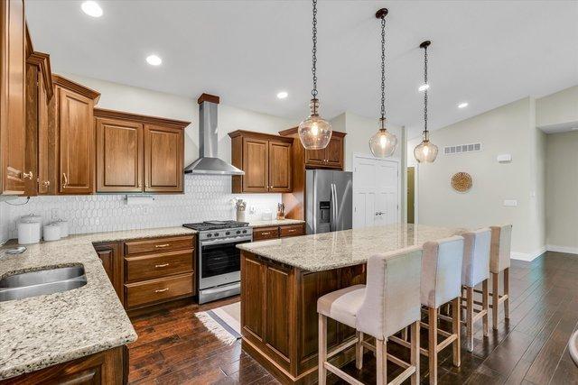 kitchen featuring dark hardwood / wood-style flooring, a kitchen island, stainless steel appliances, and wall chimney range hood