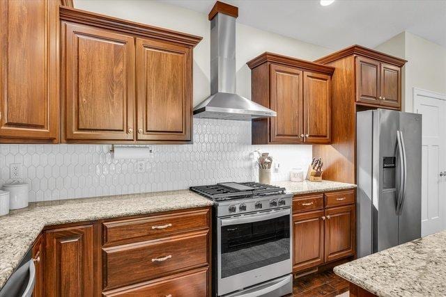 kitchen with hardwood / wood-style floors, stainless steel appliances, light stone counters, and wall chimney exhaust hood