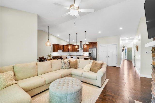 living room featuring hardwood / wood-style flooring, ceiling fan, and vaulted ceiling