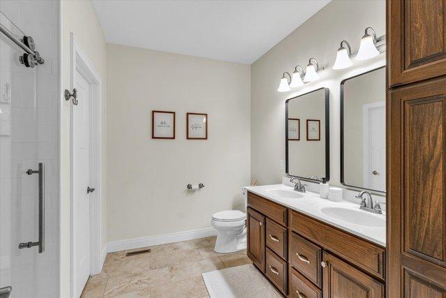 bathroom with vanity, toilet, and a shower with door