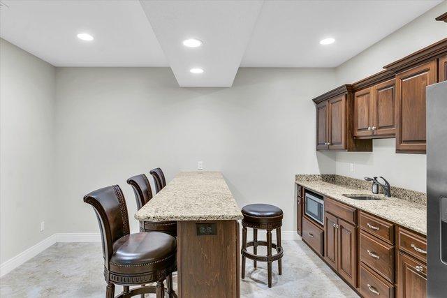 kitchen featuring light stone counters, a breakfast bar, sink, a kitchen island, and stainless steel microwave