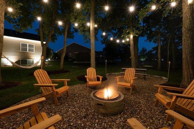 patio at night featuring a yard and an outdoor fire pit