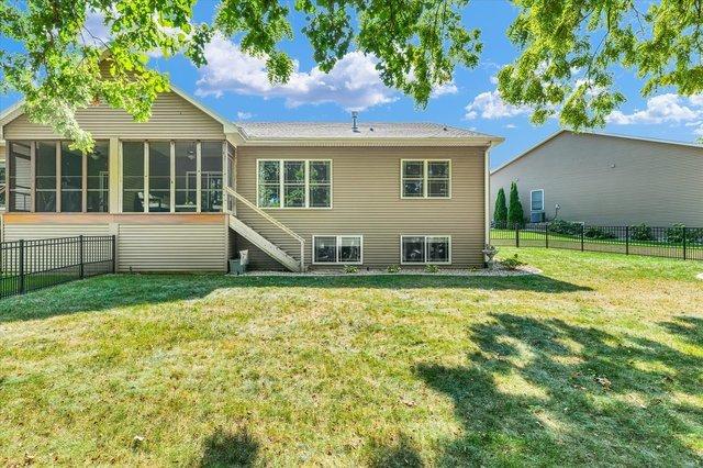 rear view of house featuring a yard and a sunroom