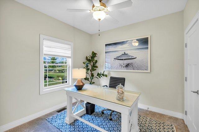 carpeted office space featuring ceiling fan