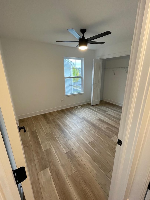 unfurnished bedroom with light wood-type flooring, a closet, and ceiling fan