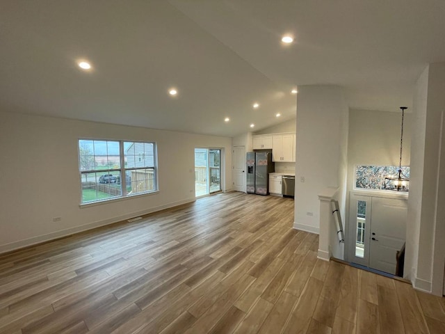 unfurnished living room with high vaulted ceiling, an inviting chandelier, and light hardwood / wood-style flooring