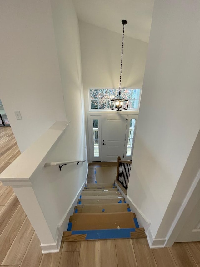 stairway featuring a chandelier, high vaulted ceiling, and wood-type flooring