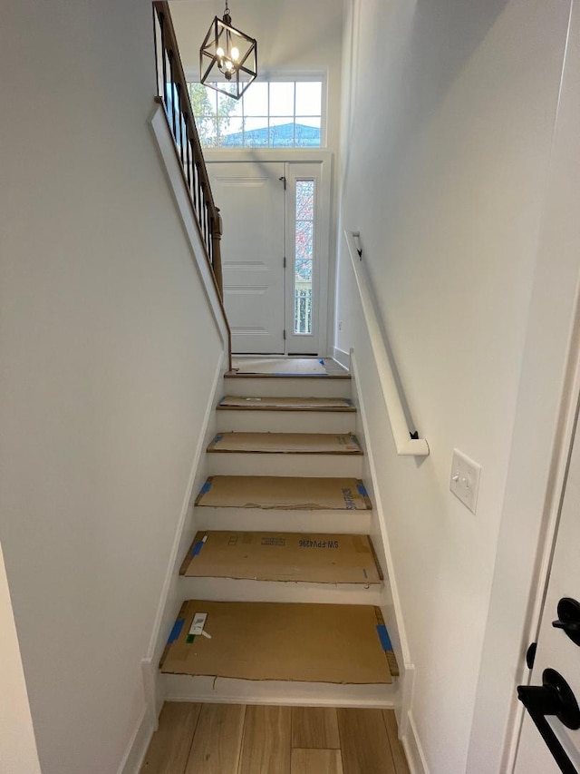 stairs with hardwood / wood-style flooring and a notable chandelier