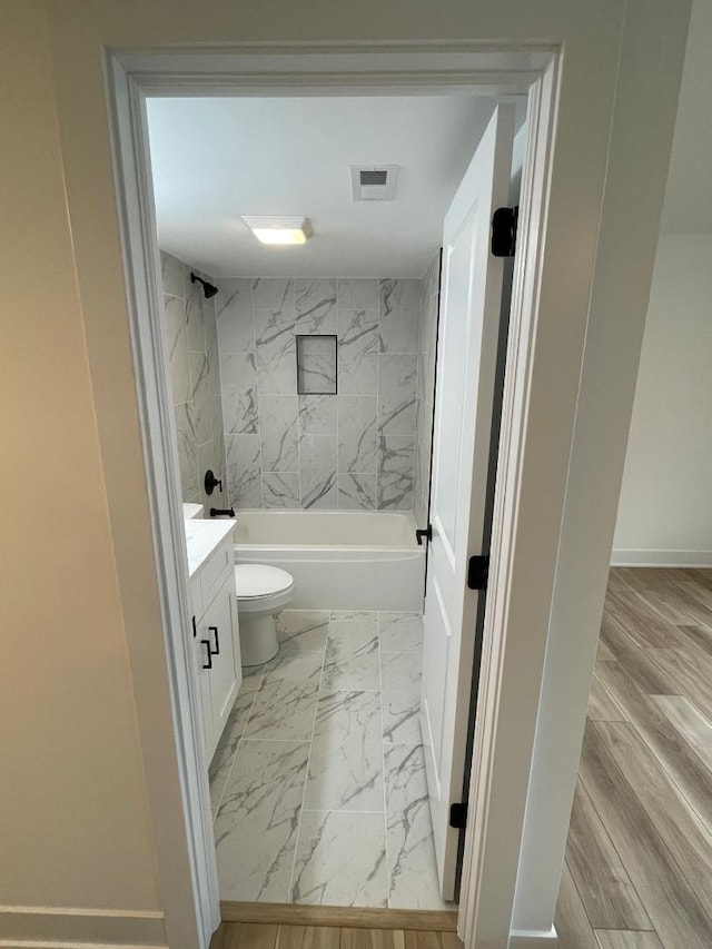 full bathroom with hardwood / wood-style flooring, vanity, toilet, and tiled shower / bath combo