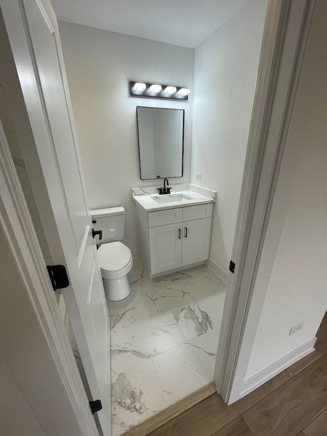 bathroom with wood-type flooring, vanity, and toilet