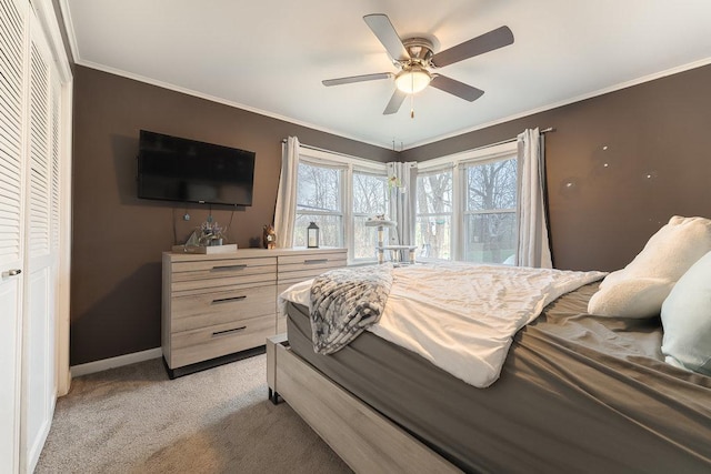 carpeted bedroom with ceiling fan, crown molding, and a closet