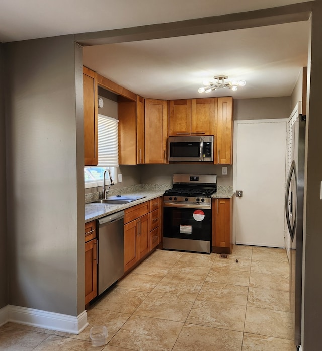 kitchen featuring light stone counters, sink, and stainless steel appliances