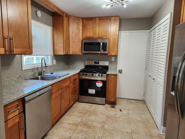 kitchen with light stone countertops, appliances with stainless steel finishes, light tile patterned floors, and sink