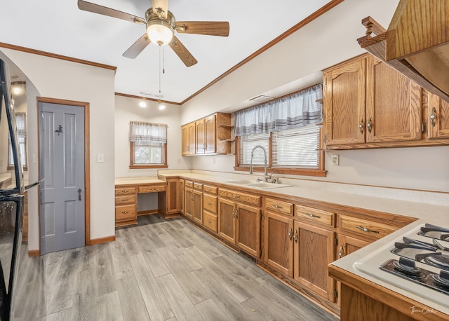 kitchen with sink, built in desk, light hardwood / wood-style flooring, white gas stovetop, and a wealth of natural light