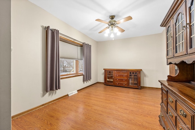 interior space featuring a ceiling fan, visible vents, light wood-style flooring, and baseboards