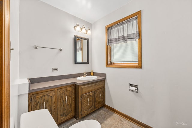 bathroom featuring toilet, vanity, and baseboards