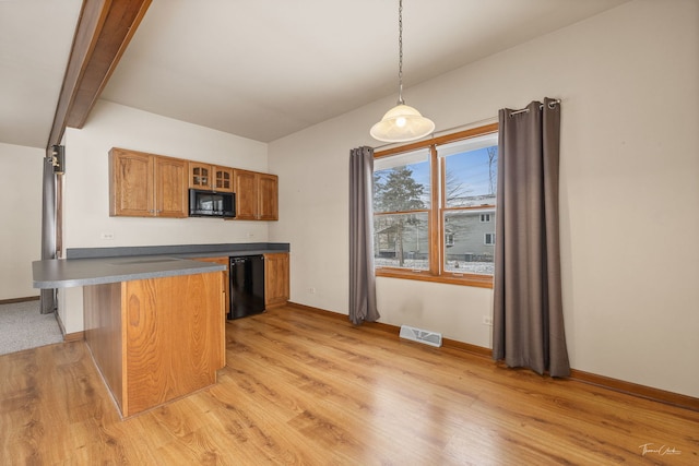 kitchen with pendant lighting, brown cabinets, dark countertops, glass insert cabinets, and black appliances