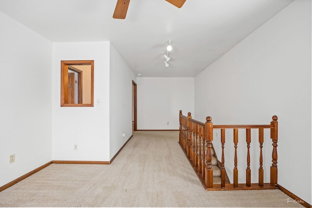 interior space featuring track lighting, light carpet, ceiling fan, and baseboards