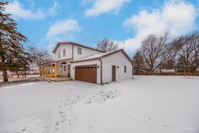 view of snow covered exterior with covered porch and a garage