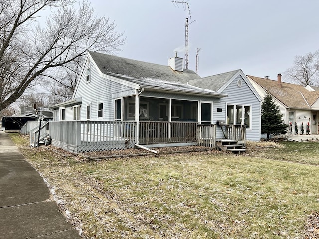 back of property featuring a sunroom, a wooden deck, and a lawn