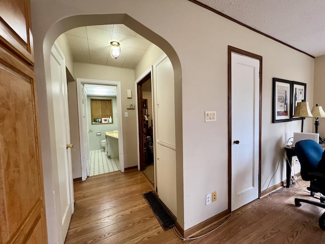 corridor with light hardwood / wood-style floors and a textured ceiling