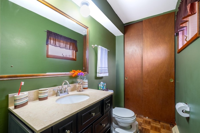 bathroom featuring vanity, toilet, and parquet floors