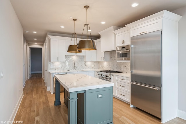 kitchen with high quality appliances, a center island, pendant lighting, and light wood-type flooring