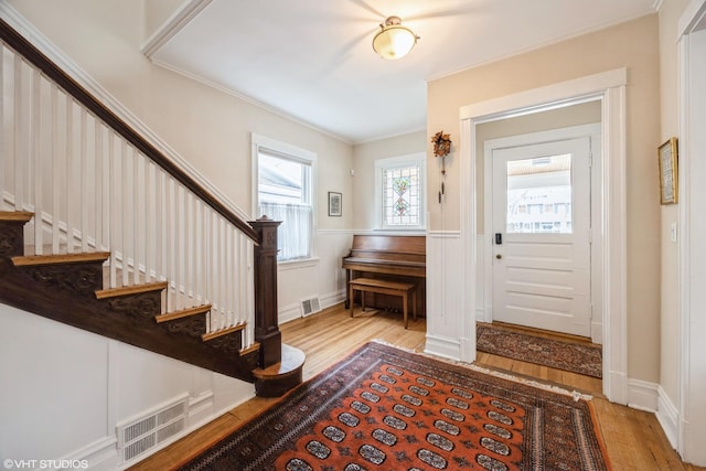 entryway with light hardwood / wood-style flooring and crown molding