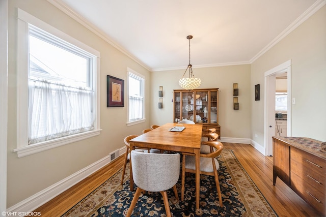 dining area with ornamental molding and light hardwood / wood-style flooring