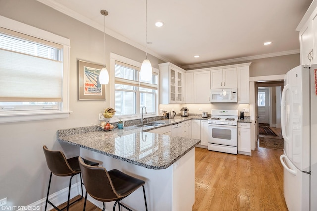 kitchen with white appliances, hanging light fixtures, white cabinetry, and kitchen peninsula