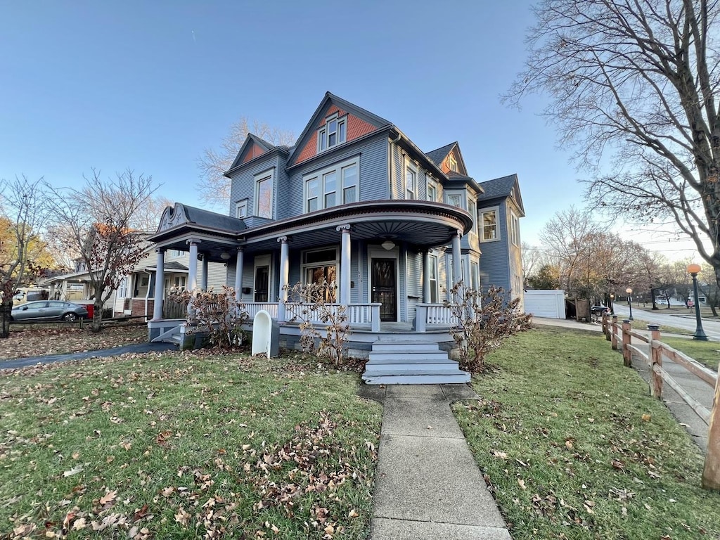 victorian house featuring covered porch and a front yard