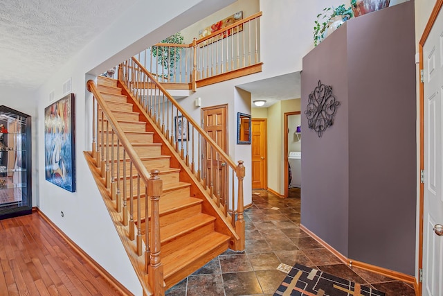 stairs with washer / dryer and a textured ceiling