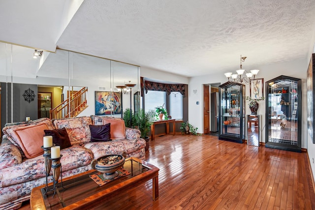 living room featuring a textured ceiling, hardwood / wood-style flooring, and an inviting chandelier