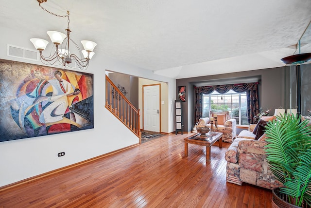 living room with lofted ceiling, wood-type flooring, a textured ceiling, and a chandelier