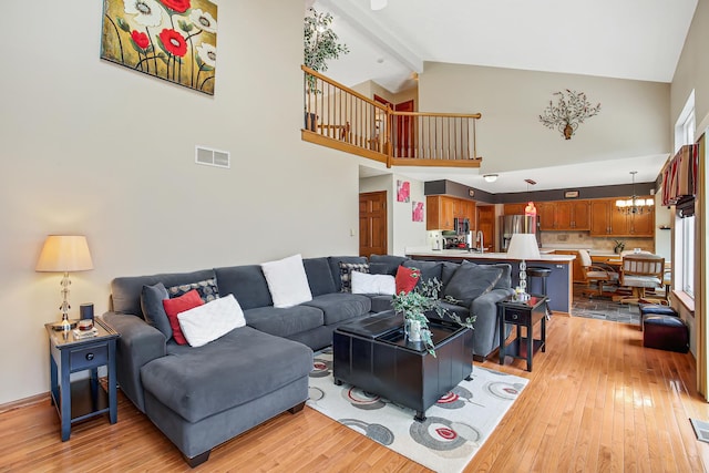 living room with high vaulted ceiling, sink, light hardwood / wood-style floors, beam ceiling, and a chandelier