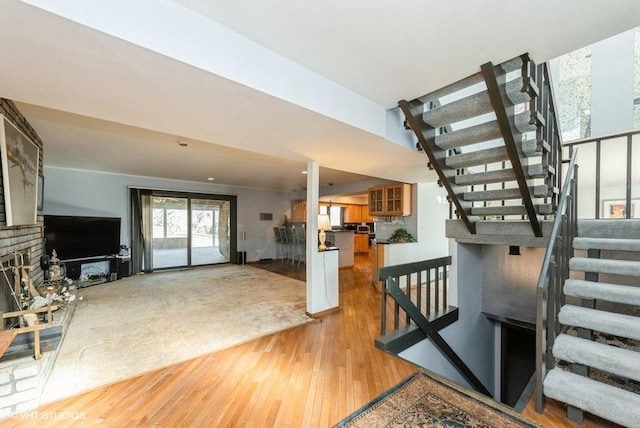 staircase with a fireplace and hardwood / wood-style floors