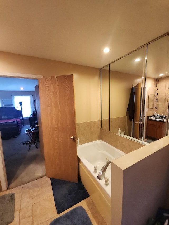 bathroom with tile patterned floors, a bathing tub, and vanity