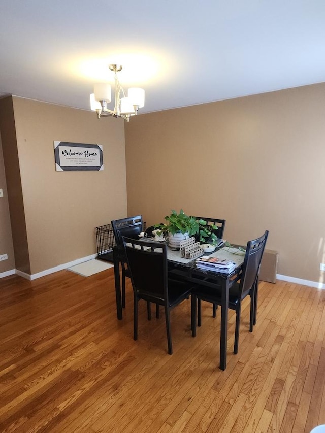 dining space with hardwood / wood-style flooring and a notable chandelier