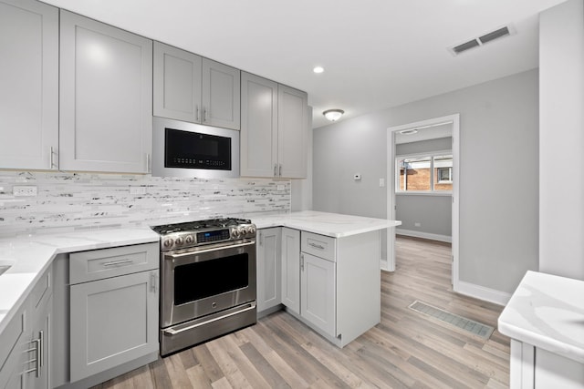 kitchen featuring gray cabinets, kitchen peninsula, appliances with stainless steel finishes, and light hardwood / wood-style flooring