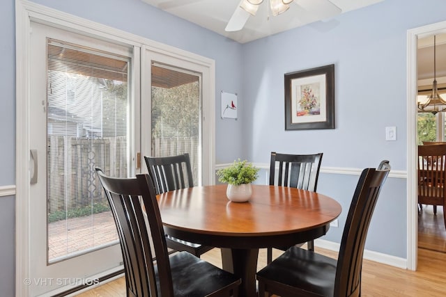 dining area with baseboards, light wood finished floors, and ceiling fan with notable chandelier