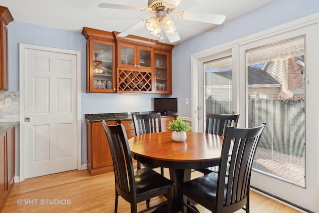 dining area with ceiling fan, a dry bar, and light wood-style flooring