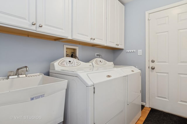 laundry room with independent washer and dryer, a sink, cabinet space, and light wood-style floors