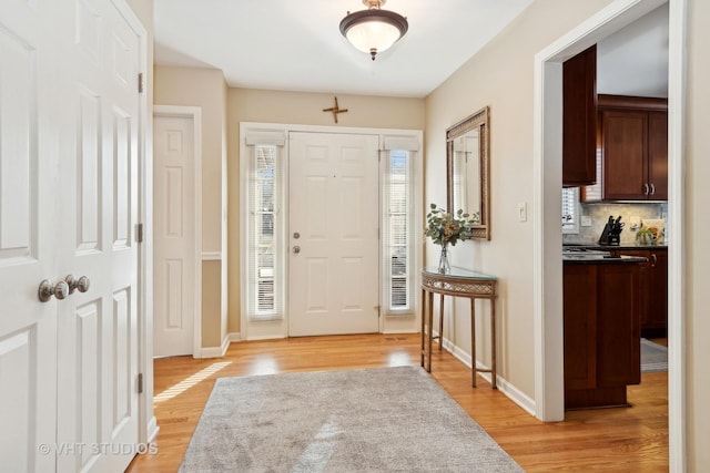 entrance foyer with baseboards, light wood-style flooring, and a healthy amount of sunlight