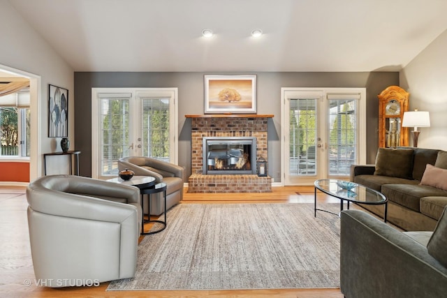 living room with lofted ceiling, french doors, a fireplace, and wood finished floors