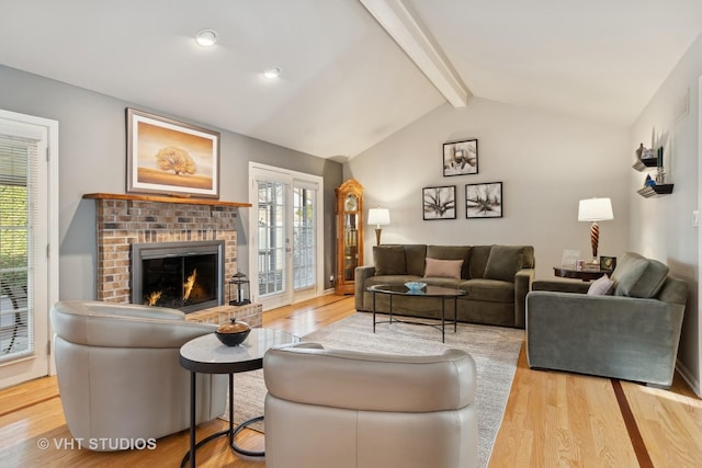 living room with vaulted ceiling with beams, a wealth of natural light, a brick fireplace, and wood finished floors