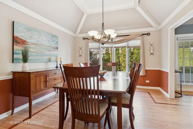 dining space featuring light wood-style flooring, baseboards, vaulted ceiling, ornamental molding, and an inviting chandelier