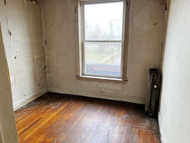 spare room featuring radiator heating unit and dark hardwood / wood-style floors