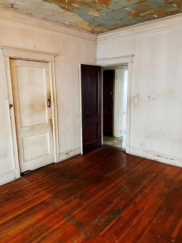 spare room with dark hardwood / wood-style flooring and crown molding