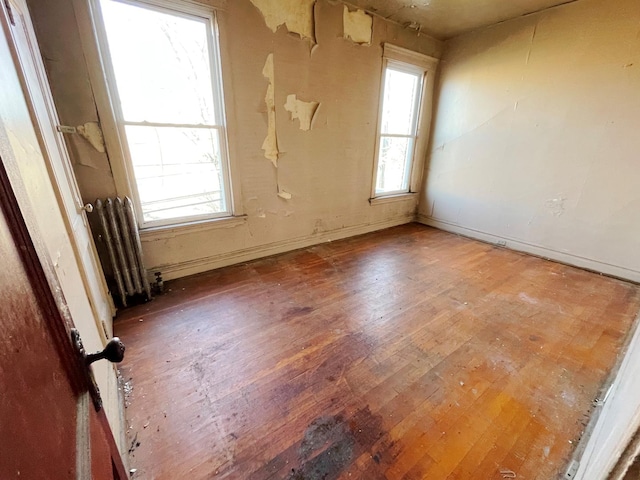 empty room with radiator, a wealth of natural light, and dark hardwood / wood-style floors